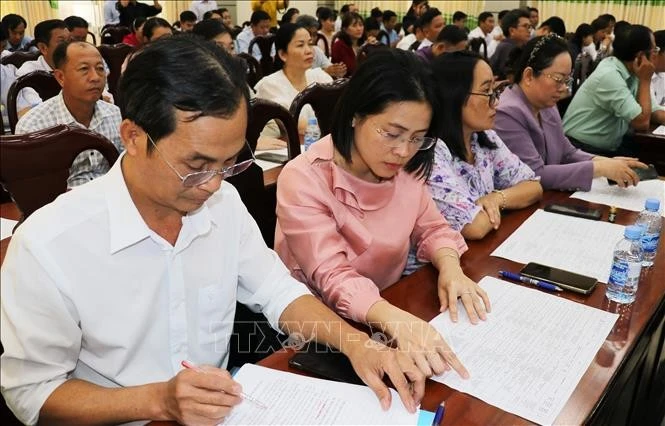 Delegates review brief biographical profiles of candidates for the 16th National Assembly at a consultative conference. (Photo: VNA)