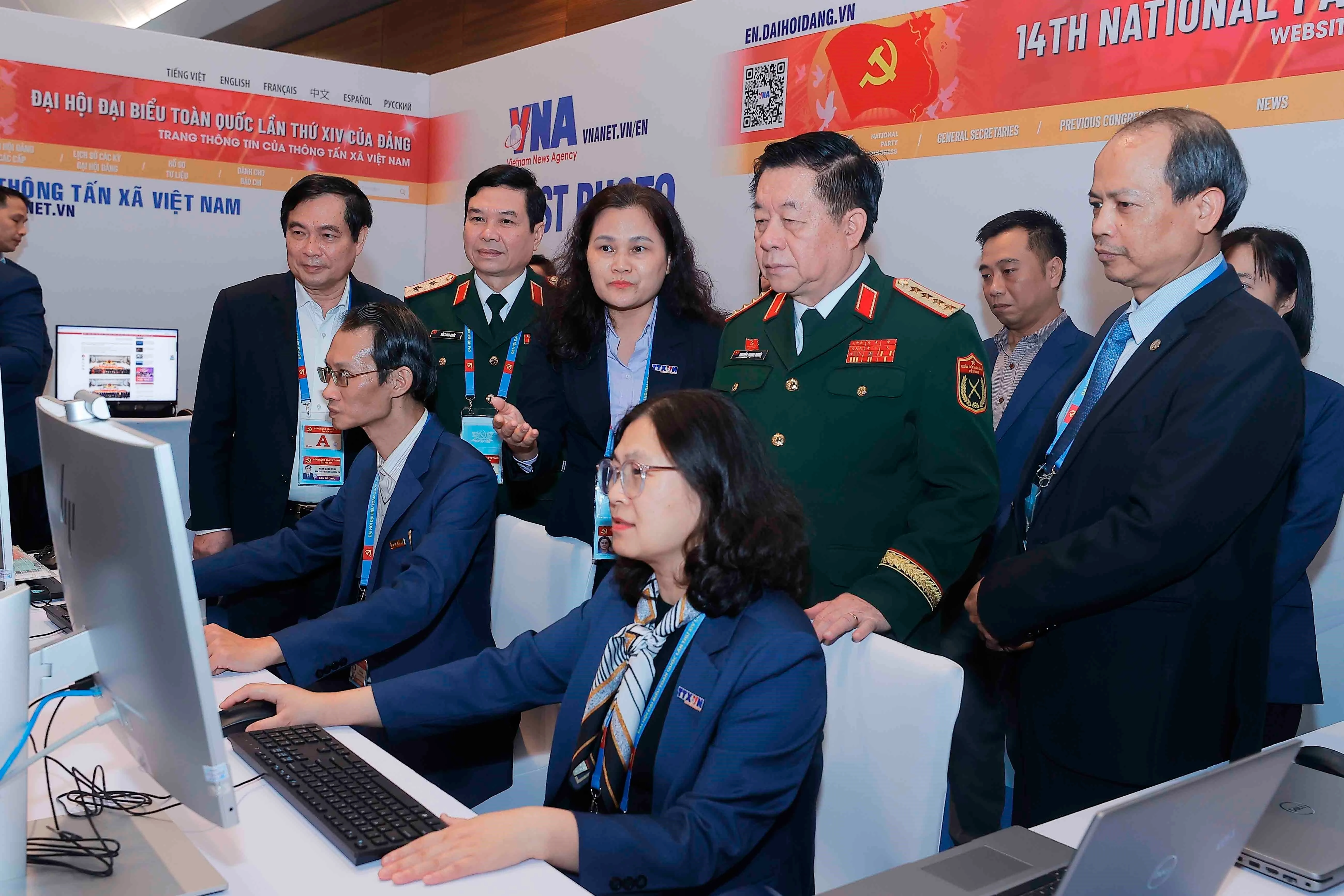 General Nguyen Trong Nghia (standing, front, second from right) visits Vietnam News Agency reporters covering the 14th National Party Congress on January 20. (Photo: VNA)