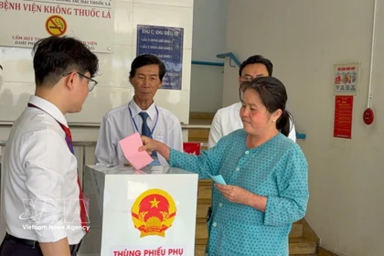 A voter under treatment at the Ho Chi Minh City Hospital of Dermato-Venereology drops her ballot into a mobile ballot box on March 15. (Photo: VNA)