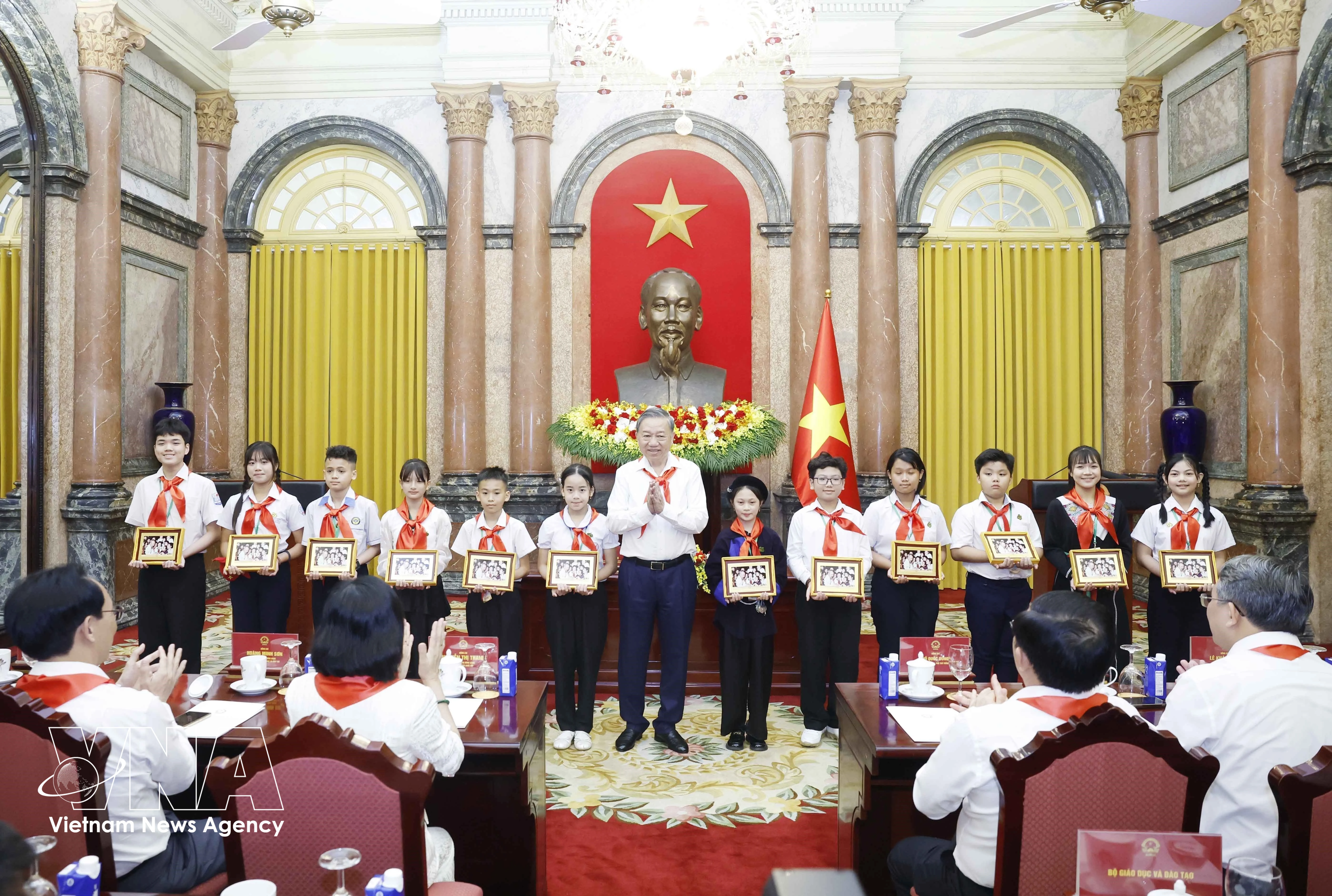 Party General Secretary and State President To Lam presents the photograph "Uncle Ho with Children" to outstanding children at the meeting on May 14. (Photo: VNA)